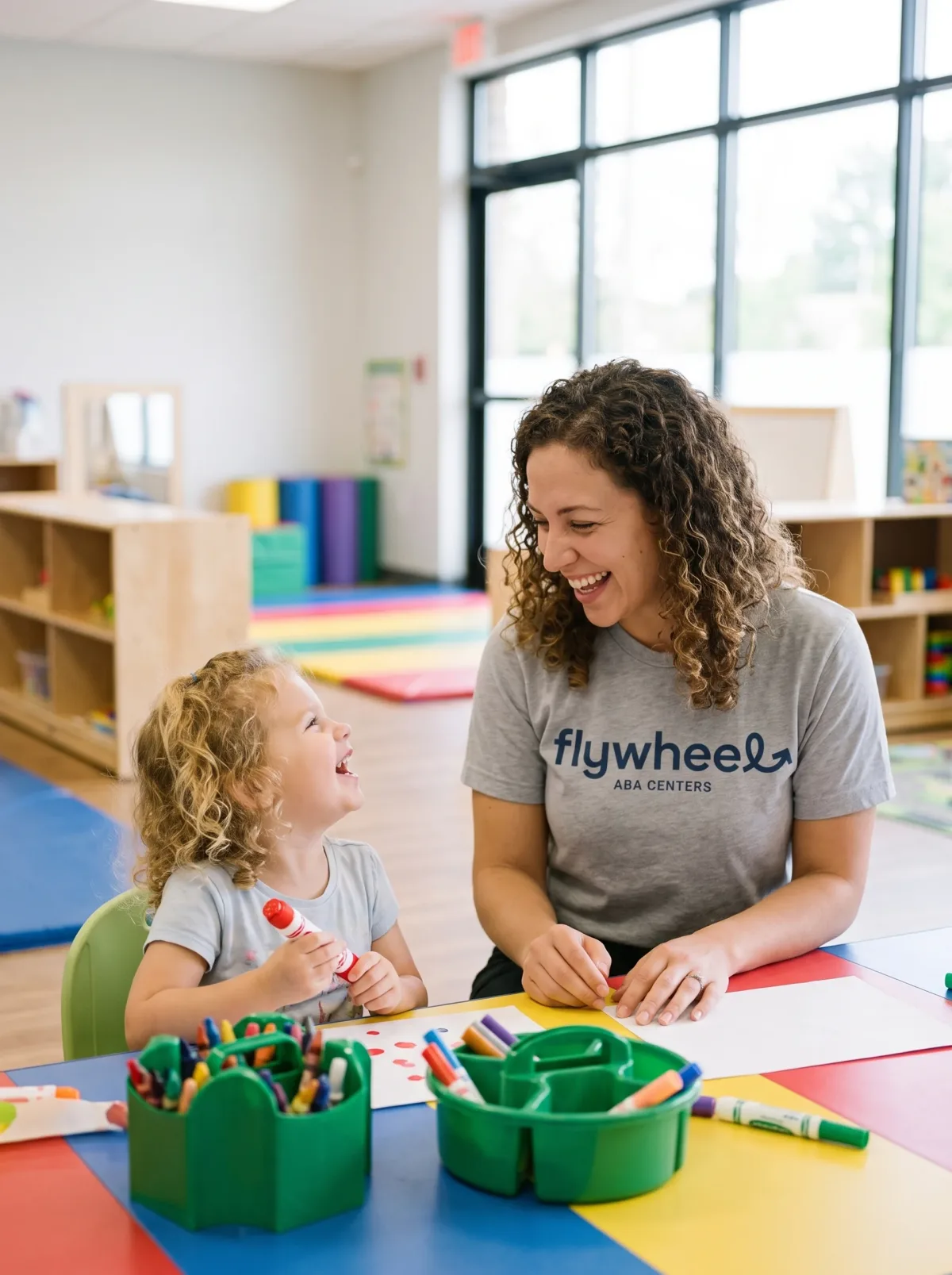 A Flywheel therapist laughing with a young girl during an art activity at the center
